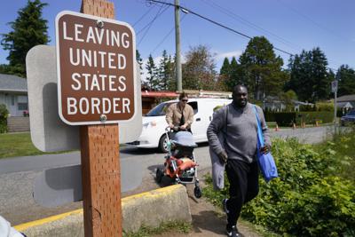 Los residentes canadienses Philip Owira (derecha) y Katherine Nichol cruzan la frontera de Canadá hacia Blaine, Washington, para visitar a un amigo, el martes 8 de junio de 2021. (AP Foto/Elaine Thompson)
