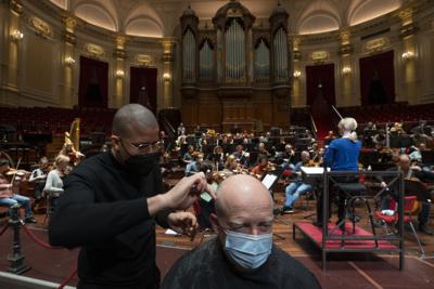 Gente se corta el pelo durante un ensayo en el Concertgebouw (sala de concertos) en Amsterdam, 19 de enero de 2002. Museos, teatros y salas recibieron a negocios que no pudieron abrir debido a las medidas contra el coronavirus. (AP Foto/Peter Dejong)