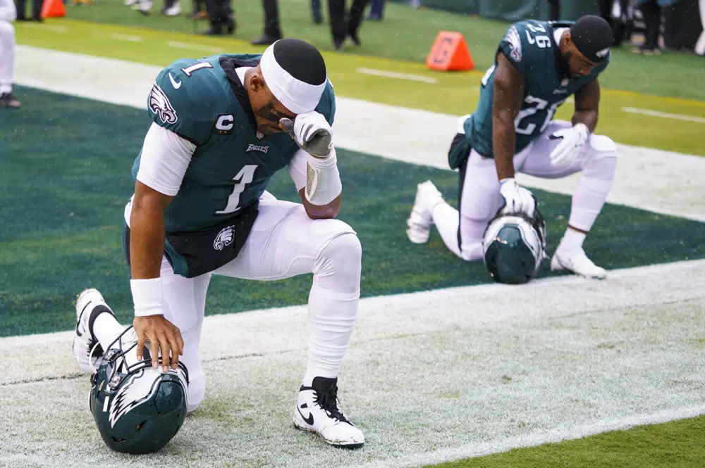 FILE - Philadelphia Eagles quarterbacks Jalen Hurts (1) kneels with running back Miles Sanders (26) during the NFL football game against the Jacksonville Jaguars, Sunday, Oct. 2, 2022, in Philadelphia. Public display of faith is nothing new in football or sports.(AP Photo/Chris Szagola, File)