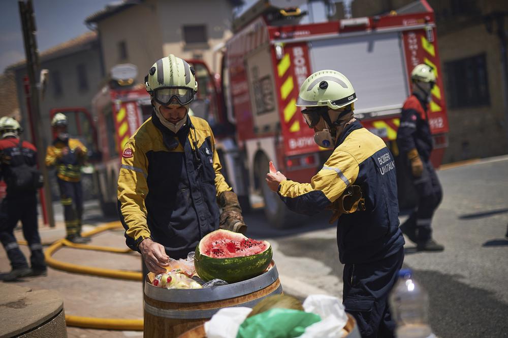 Firefighters eat watermelon during a break in San Martin de Unx in northern Spain, Sunday, June 19, 2022. Firefighters in Spain are struggling to contain wildfires in several parts of the country which as been suffering an unusual heat wave for this time of the year. (AP Photo/Miguel Oses)
