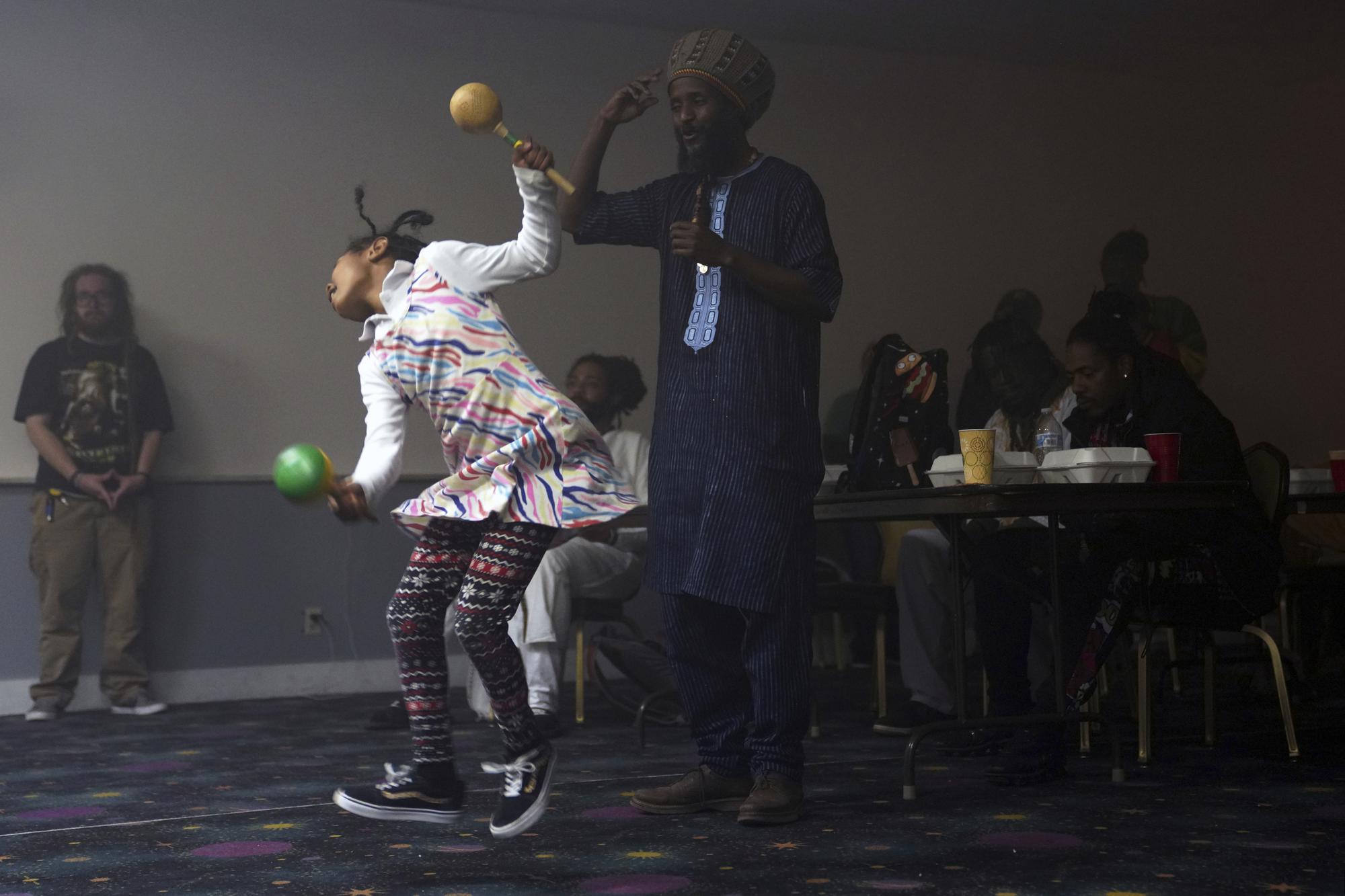 La emperatriz Imani Tafari, de 8 años, y Ras Mo bailan durante un evento de la Coalición Rastafari que marca el 91 aniversario de la coronación del difunto emperador etíope Haile Selassie I en Columbus, Ohio, el martes 2 de noviembre de 2021. El evento del día de la coronación incluyó el canto, el tamborileo tradicional nyabinghi y la lectura de salmos, que son el núcleo de las celebraciones navideñas rastafari.  (Foto AP / Emily Leshner)