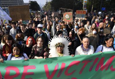 Personas marchan en Bruselas para presionar a los líderes mundiales a tomar medidas más audaces para combatir el cambio climático, el 10 de octubre de 2021, en Bélgica. (AP Foto/Geert Vanden Wijngaert)