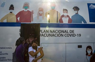 Mujeres salen de un autobús que se usa para inyectar la vacuna contra COVID-19 en Santiago, Chile, el miércoles 26 de mayo de 2021. (AP Foto/Esteban Felix)