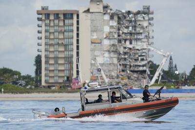 Una embarcación de la Guardia Costera patrulla por delante de Champlain Towers South, un edificio de apartamentos parcialmente derruido, antes de la visita del presidente de Estados Unidos, Joe Biden, el 1 de julio de 2021, en Surfside, Florida. (AP Foto/Mark Humphrey)