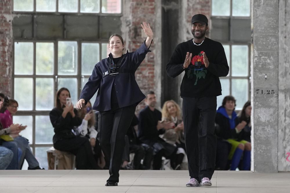 Fashion designers Rushemy Botter and Lisi Herrebrugh, left, acknowledge applause after the presentation of Botter ready-to-wear Spring/Summer 2023 fashion collection, Tuesday, Sept. 27, 2022 in Paris. (AP Photo/Francois Mori)