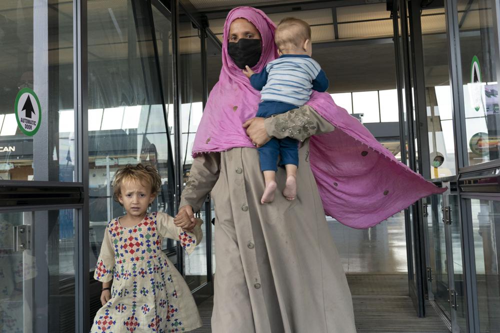 Families evacuated from Kabul, Afghanistan, walk through the terminal before boarding a bus after they arrived at Washington Dulles International Airport, in Chantilly, Va., on Friday, Aug. 27, 2021. (AP Photo/Jose Luis Magana)