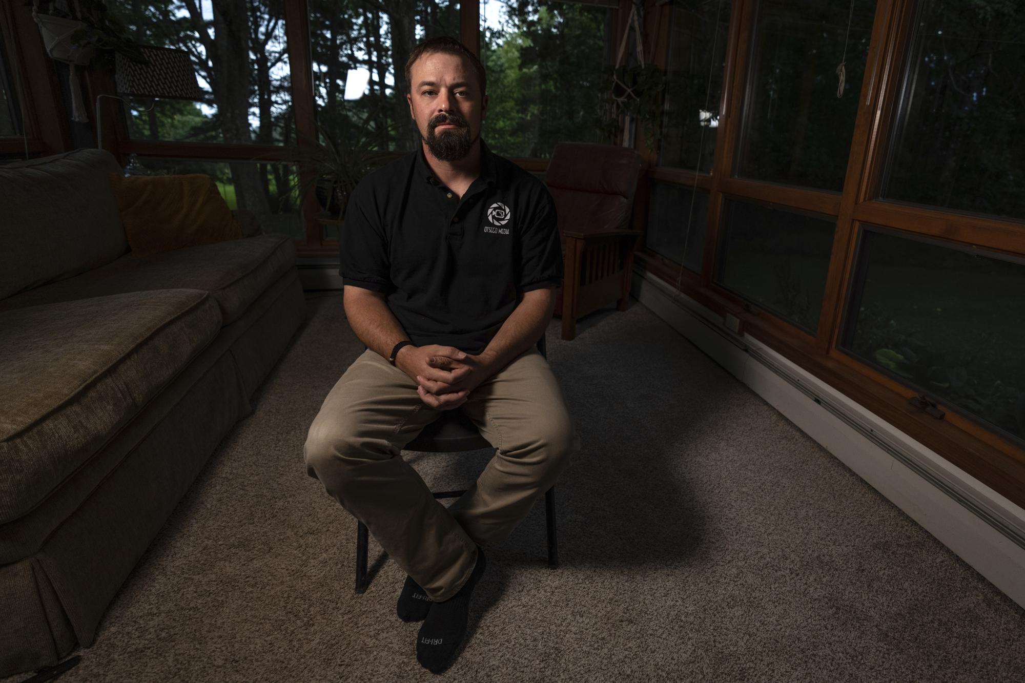 Korey Rowe poses for a photo at his home in Oneonta, N.Y. on Thursday, Aug. 12, 2021. Korey Rowe served tours in Iraq and Afghanistan and returned to the U.S. in 2004 traumatized and disillusioned. His experiences overseas and nagging questions about Sept. 11, 2001 convinced him America's leaders were lying about what happened that day and the wars that followed. (AP Photo/Robert Bumsted)