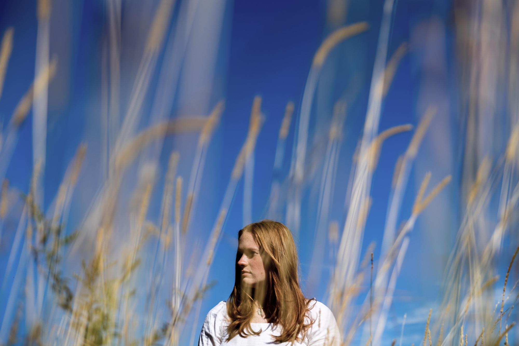 Jackie Hegarty, a rising senior at Newtown High School, poses for a photo at Holcombe Hill Wildlife Preserve, Thursday, Aug. 18, 2022, in Newtown, Conn. Hegarty, a triplet, was in second grade doing yoga with her classmates when the shooter opened fire right across the hall. (AP Photo/Julia Nikhinson)