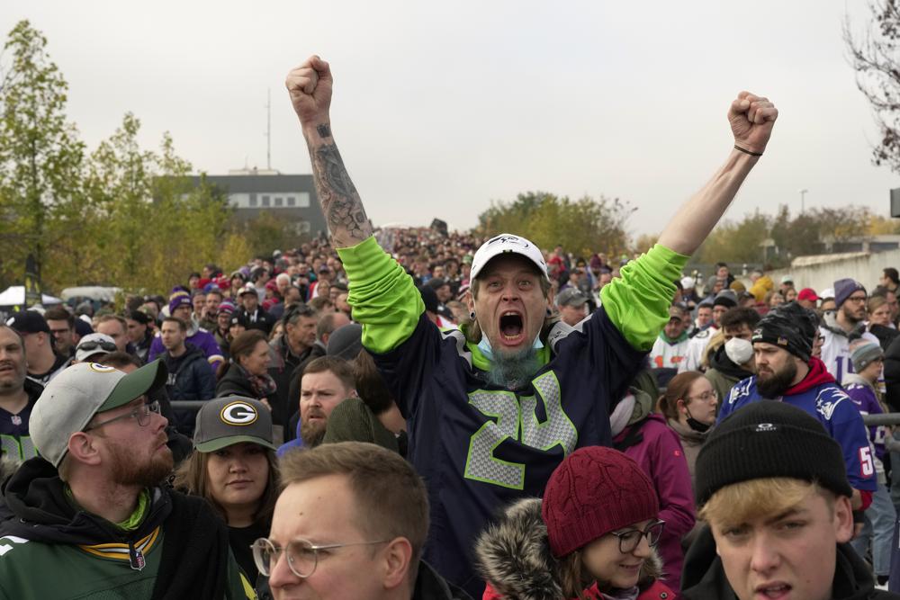 A fan of the Seahawks cheers as he arrives with a crowd of fans for a NFL match between Tampa Bay Buccaneers and Seattle Seahawks at the Allianz Arena in Munich, Germany, Sunday, Nov. 13, 2022. (AP Photo/Markus Schreiber)