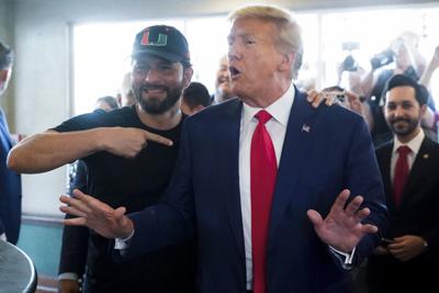 A supporter stands with former President Donald Trump as he visits Versailles restaurant on Tuesday, June 13, 2023, in Miami. Trump appeared in federal court Tuesday on dozens of felony charges accusing him of illegally hoarding classified documents and thwarting the Justice Department's efforts to get the records back. (AP Photo/Alex Brandon)