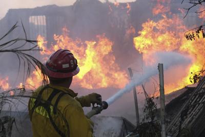 Un bombero trata de sofocar las llamas en una casa al paso del Incendio Sur en Lytle Creek, en el condado San Bernardino, al norte de Rialto, California, el miércoles 25 de agosto de 2021. (AP Foto/Ringo H.W. Chiu)