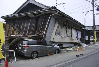 Un automóvil es visto aplastado por una casa derrumbada después de un fuerte terremoto en la ciudad de Suzu, prefectura de Ishikawa, norte de Japón, el viernes 5 de mayo de 2023. Un fuerte terremoto sacudió el viernes por la tarde cerca del centro de Japón, pero no hubo informes de una amenaza de tsunami. (Kyodo News vía AP)