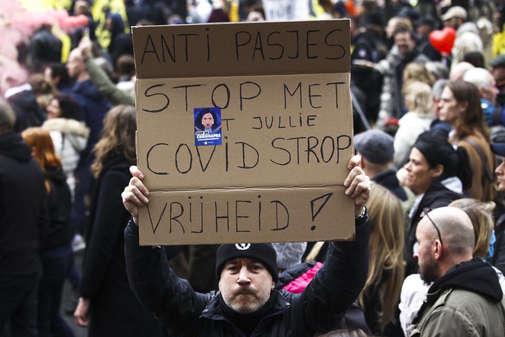 FILE - A man holds up a poster that reads: 'Against Passes. Stop the COVID noose. Freedom', during a demonstration against the reinforced measures of the Belgium government to counter the latest spike of the coronavirus in Brussels, Belgium, Sunday, Nov. 21, 2021. The coronavirus's omicron variant kept a jittery world off-kilter Wednesday Dec. 1, 2021, as reports of infections linked to the mutant strain cropped up in more parts of the globe, and one official said that the wait for more information on its dangers felt like “an eternity.” (AP Photo/Olivier Matthys, File)