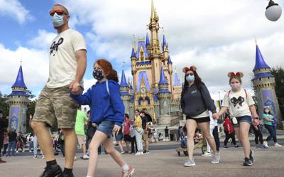 ARCHIVO - En esta foto del 21 de diciembre del 2020, una familia pasa junto al Castillo de Cenicienta en el Magic Kingdom, en el Walt Disney World en Lake Buena Vista, Florida. (Joe Burbank/Orlando Sentinel via AP)