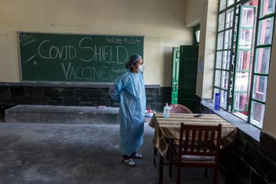 Un enfermera tibetana exiliada se coloca el uniforme de protección antes de participar en la campaña de vacunación, en un centro en Dharmsala, India, el 1 de julio de 2021. (AP Foto/Ashwini Bhatia)