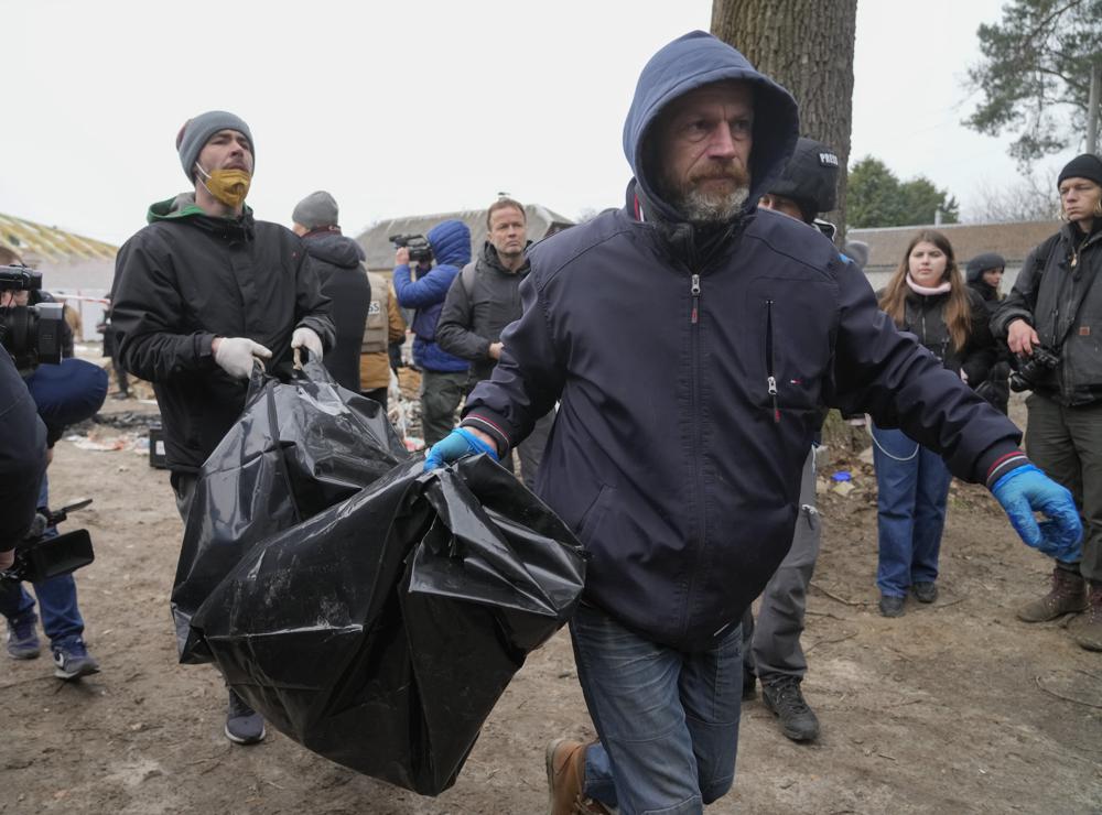 Police carry a dead body of one of six civilians - three women, one teenager girl and two men who were found in Bucha, close to Kyiv, Ukraine, Tuesday, Apr. 5, 2022. Ukraine’s president plans to address the U.N.’s most powerful body after even more grisly evidence emerged of civilian massacres in areas that Russian forces recently left. (AP Photo/Efrem Lukatsky)