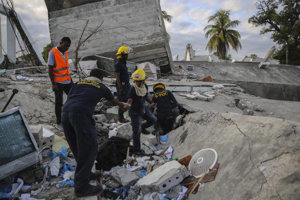 Firefighters search for survivors inside a collapsed building, after Saturday´s 7.2 magnitude earthquake in Les Cayes, Haiti, Sunday, Aug. 15, 2021. (AP Photo/Joseph Odelyn)