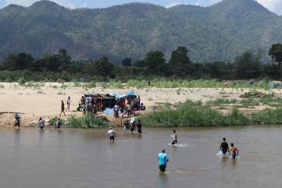 Refugiados de Myanmar cruzan el río Moei a pie con insumos donados que traen desde Mae Sot (Tailandia) el 7 de febrero del 2022. (AP Photo)
