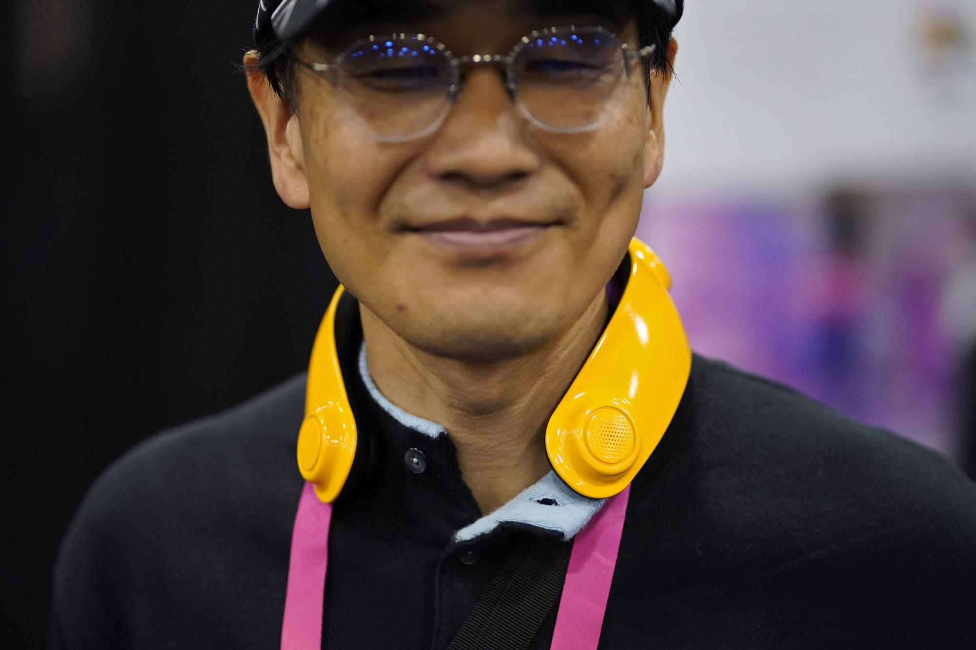Exhibitor Toru Yamanaka wears a Loovic augmented reality device during CES Unveiled before the start of the CES tech show, Tuesday, Jan. 3, 2023, in Las Vegas. The IoT device, worn around the neck, uses tactile notifications and bone conduction audio to help guide the user without having to constantly look at a map app on their phone. (AP Photo/John Locher)
