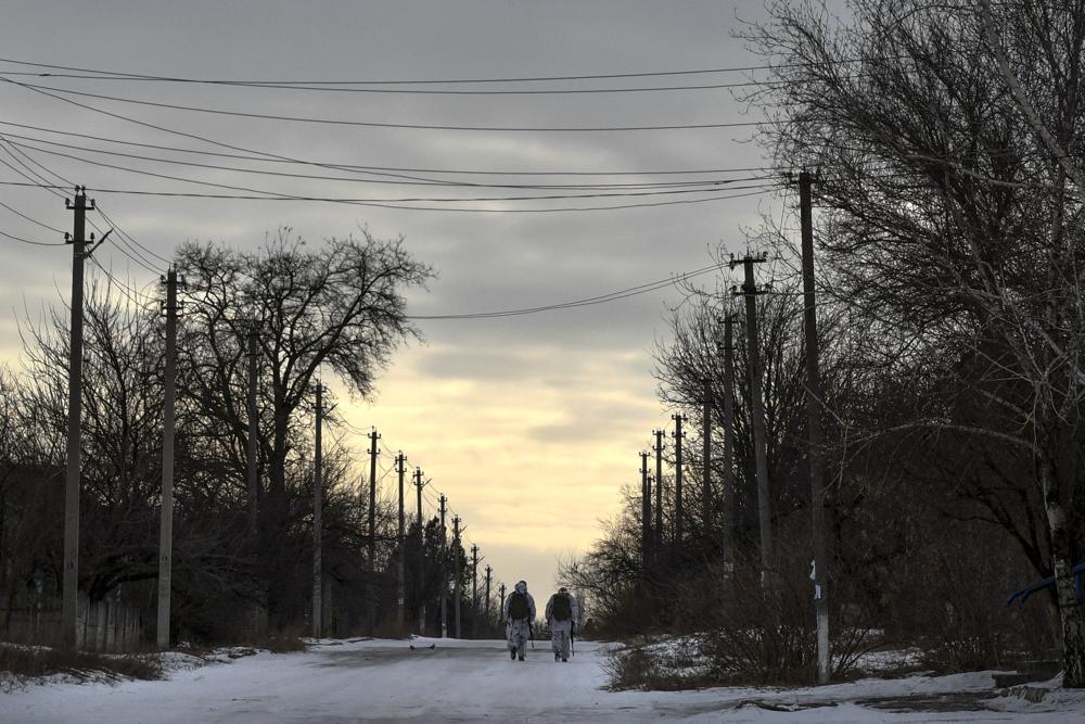 FILE - Ukrainian servicemen patrol a street toward the frontline with Russia-backed separatists in Verkhnotoretske village in Yasynuvata district, Donetsk region, eastern Ukraine, Saturday, Jan. 22, 2022. Ukrainians in the country's east are likely to be on the front lines of war if it comes, but they are far from the people making decisions about their fate. (AP Photo/Andriy Andriyenko, File)