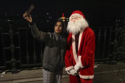 Una mujer se toma una selfie con un hombre disfrazado de Santa Claus en Hyderabad, India, el sábado 25 de diciembre de 2021. (Foto AP/Mahesh Kumar A.)