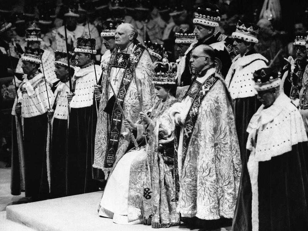 FILE - Britain's Queen Elizabeth II is crowned the Monarch of Britain holding the Royal Scepter, sat on throne, wearing St. Edward's crown, at Westminster Abbey, in London, June 2, 1953. Britain’s royal family turns the page on a new chapter with the coronation of King Charles III. Charles ascended the throne when his mother, Queen Elizabeth II, died last year. But the coronation Saturday is a religious ceremony that provides a more formal confirmation of his role as head of state and titular head of the Church of England. (AP Photo, File)