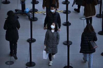 Gente con mascarillas para protegerse contra el COVID-19 espera a entrar en una tienda en un centro comercial al aire libre en Beijing, el sábado 13 de noviembre de 2021. (AP Foto/Mark Schiefelbein)