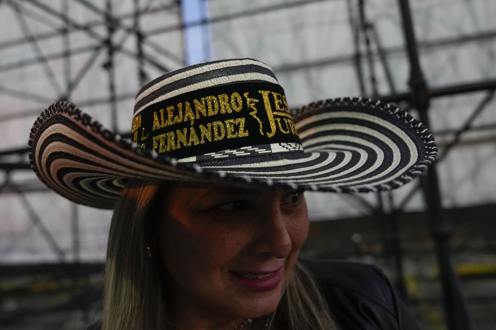 ARCHIVO - Una fan usa un sombrero con los nombres del cantante mexicano Alejandro Fernández y la cantante colombiana Jessi Uribe mientras espera en fila para entrar a su concierto en Caracas el 3 de marzo de 2022. Después de años, grandes estrellas están volviendo a incluir en sus giras a Venezuela, donde los boletos pueden costar entre 55 y 600 dólares.  (Foto AP/Ariana Cubillos, archivo)
