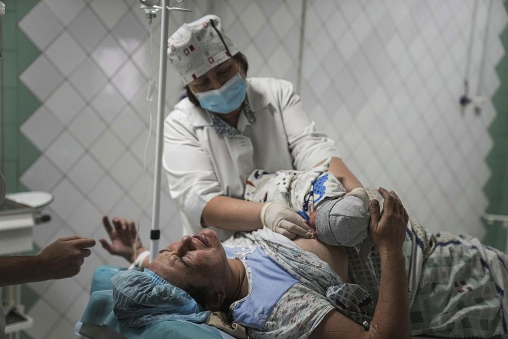 ممرضة أمومة تعرض مولودًا جديدًا لامرأة ولدت في مستشفى للولادة تم تحويلها إلى جناح طبي في ماريوبول ، أوكرانيا ، الثلاثاء ، 1 مارس ، 2022. أدت الضربات الروسية على مدينة ماريوبول الساحلية الجنوبية إلى إصابة العديد من الأشخاص بجروح خطيرة.  (AP Photo / Evgeniy Maloletka)