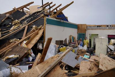 Guthrie Matherne (izquierda) y Blakland Matherne de pie el lunes 6 de septiembre de 2021 junto a los restos de su negocio, destruido por el huracán Ida, en Lockport, Luisiana. (AP Foto/John Locher)