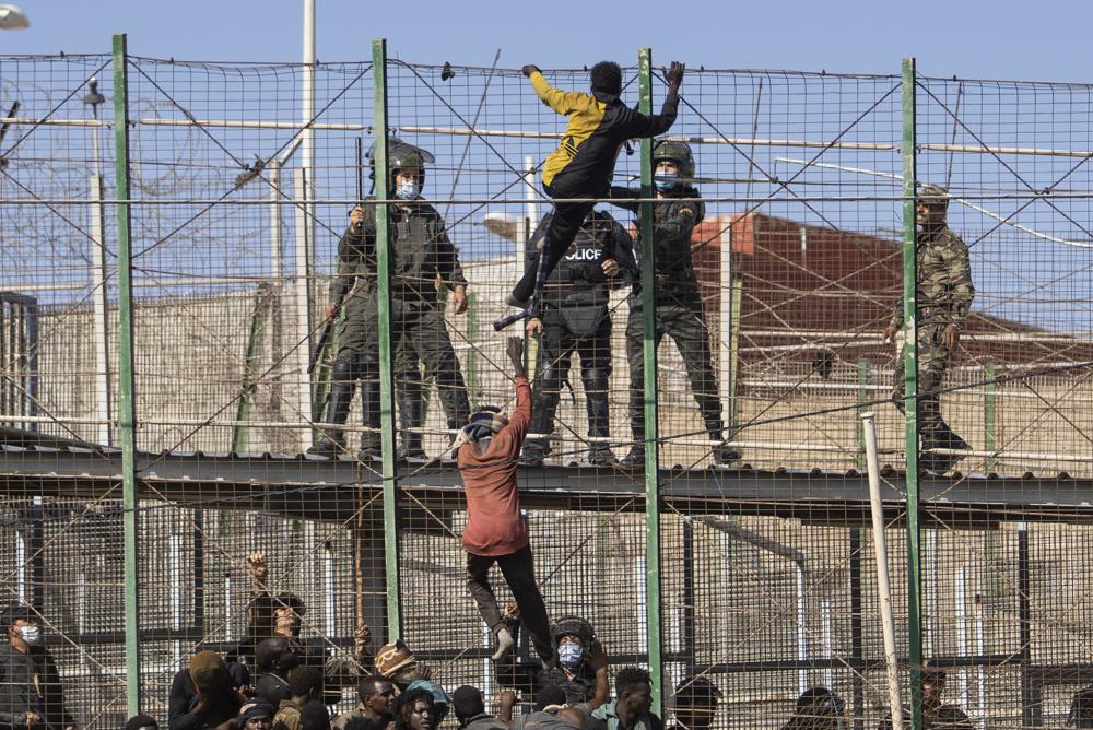 Migrants climb the fences separating the Spanish enclave of Melilla from Morocco in Melilla, Spain, Friday, June 24, 2022. Dozens of migrants stormed the border crossing between Morocco and the Spanish enclave city of Melilla on Friday in what is the first such incursion since Spain and Morocco mended diplomatic relations last month. (AP Photo/Javier Bernardo)