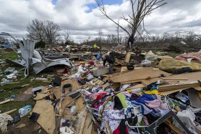 ARCHIVO - Gente entre los restos de un tornado nocturno en Sullivan, Indiana, el 1 de abril de 2023. (AP Foto/Doug McSchooler, Archivo)