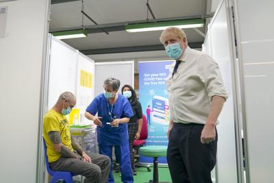 El primer ministro británico, Boris Johnson, a la derecha, visita un centro de vacunación COVID-19 en el estadio Stoke Mandeville en Aylesbury, Inglaterra, el lunes 3 de enero de 2022. (Steve Parsons/Pool vía AP)