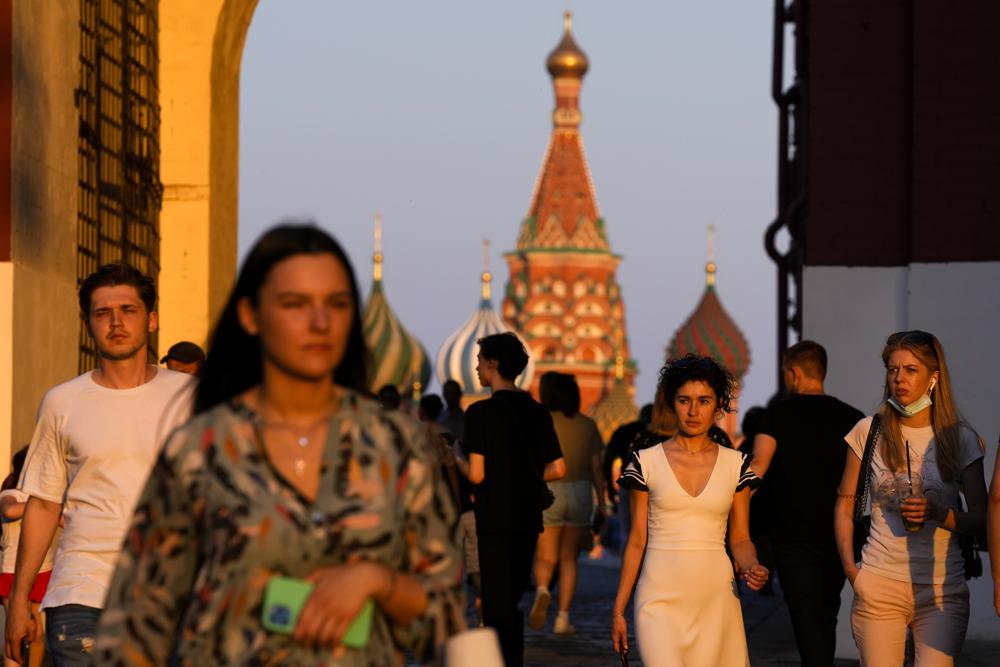 La gente, la mayoría sin mascarillas, camina en la Plaza Roja durante la puesta de sol en Moscú, Rusia, el jueves 24 de junio de 2021. Un ambicioso plan de vacunar a 30 millones de rusos a mediados de junio contra el coronavirus se ha quedado corto en un tercio, y el país ha comenzado a ver un aumento en las nuevas infecciones diarias.  (Foto AP / Alexander Zemlianichenko)