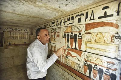 Mostafa Waziri, secretario general del Consejo Supremo de Antigüedades de Egipto, mira jeroglíficos dentro de una tumba recién descubierta cerca de la famosa pirámide escalonada de Zoser, en Saqqara, al sur de Egipto, el 19 de marzo del 2022. (AP Foto/Sayed Hassan)