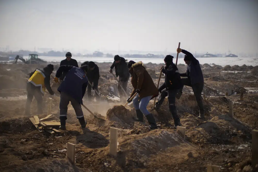 Municipal grave diggers bury the bodies of four people, three of the them not claimed claimed relatives, in a makeshift cemetery on the outskirts of Elbistan, Turkey, Saturday, Feb. 11, 2023. Rescue crews on Saturday pulled more survivors, including entire families, from toppled buildings despite diminishing hopes as the death toll of the enormous quake that struck a border region of Turkey and Syria five days continued to rise. (AP Photo/Francisco Seco)