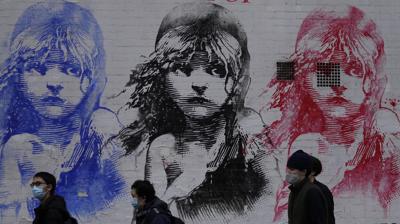 Tres personas hacen fila afuera de un teatro para una presentación de Los Miserables, el martes 28 de diciembre de 2021, en Londres. (AP Foto/Alastair Grant)