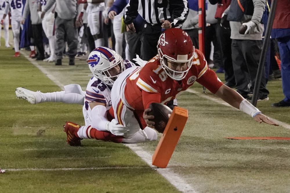 El mariscal de campo de los Kansas City Chiefs, Patrick Mahomes (15), anota en una carrera de touchdown de 8 yardas por delante del profundo de los Buffalo Bills, Micah Hyde (23), durante la primera mitad de un partido de fútbol de la ronda divisional de la NFL, el domingo 23 de enero de 2022, en Kansas City, Missouri (Foto AP/Charlie Riedel)