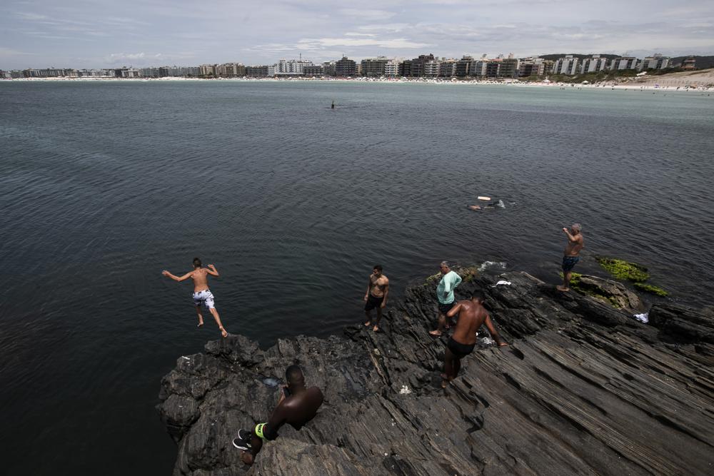 Bathers dive into the waters of Fort Beach in Cabo Frio, Brazil, Wednesday, Dec. 15, 2021. Brazil became one of the first countries in the world to approve Bitcoin exchange-traded funds, second only to Canada. In and around Cabo Frio, where some had seen their friends and neighbors reap rewards by investing their life savings in the cryptocurrency investment firm G.A.S Consulting & Technology, many began to fear the cost of missing out. (AP Photo/Bruna Prado)