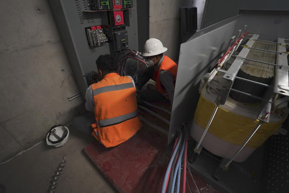 Trabajadores preparan cables para los paneles solares instalados por Pireos Power en el techo de una bodega en el Estado de México el miércoles 13 de abril de 2022. (AP Foto/Marco Ugarte)
