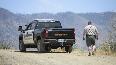 Un agente de policía del condado de Mariposa revisa una zona remota en el noreste de la localidad de Mariposa, California, el miércoles 18 de agosto de 2021, cerca del sitio en el que una familia y su perro fueron encontrados sin vida. (Craig Kohlruss/The Fresno Bee vía AP)