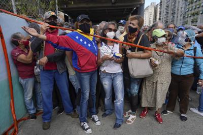 En esta imagen de archivo, tomada el 16 de septiembre de 2021, residentes esperan detrás de una cinta que sirve de barrera ante un centro de vacunación, donde buscan recibir la segunda dosis de la rusa Sputnik V contra el COVID-19, en Caracas, Venezuela. (AP Foto/Ariana Cubillos, archivo)