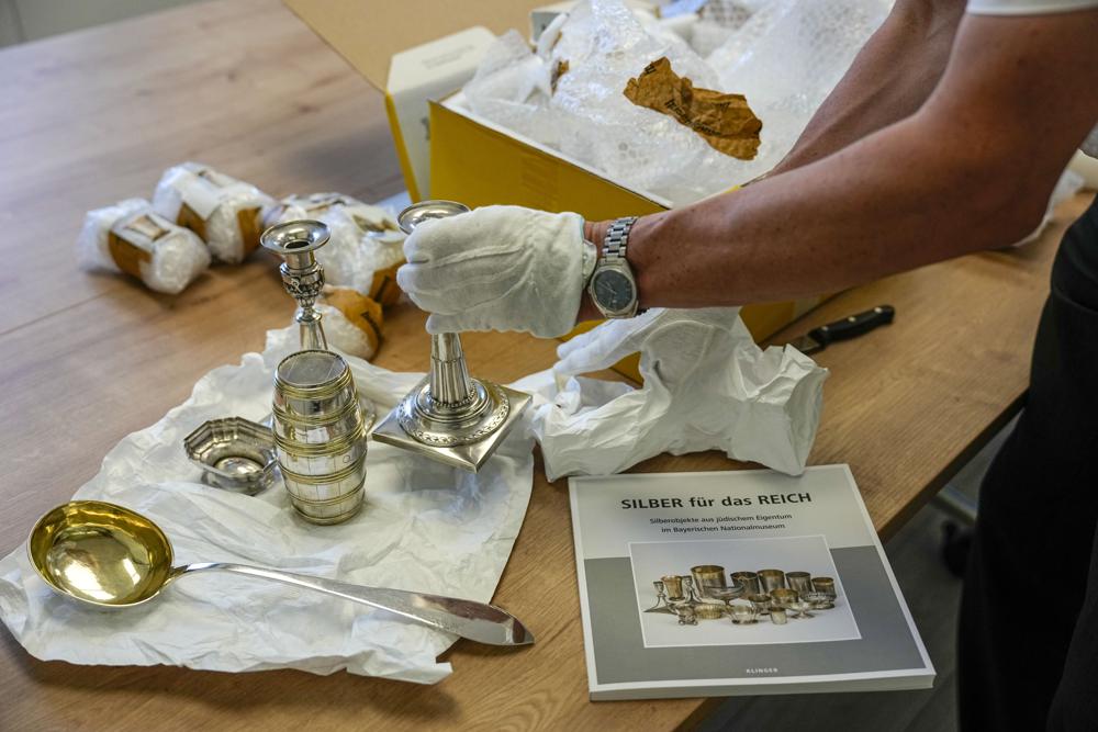 Art historian Matthias Weniger, from the Bavarian National Museum arranges silver owned by Jews, in Tel Aviv, Israel, Thursday, June 1, 2023. (AP Photo/Ariel Schalit)