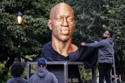 FILE - In this Thursday, Sept. 30, 2021, file photo, a sculpture of George Floyd, one of three sculptures as part of the "SEEINJUSTICE" art exhibition that also feature the likenesses of Breonna Taylor and John Lewis, is unveiled as Floyd's brother Terrence, second from left, looks at Union Square in the Manhattan borough of New York. The statue honoring Floyd was vandalized on Sunday, Oct. 3, police said. (AP Photo/John Minchillo, File)