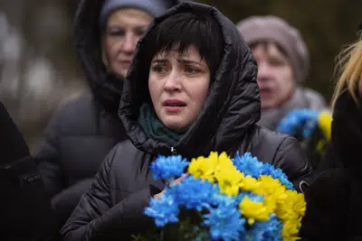 Una mujer llora durante un oficio fúnebre en el primer aniversario del inicio de la invasión rusa a Ucrania, en un cementerio en Bucha, Ucrania, viernes 24 de febrero de 2023. (AP Foto/Emilio Morenatti)