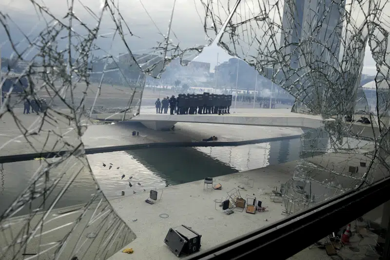 FILE - Police stand on the other side of a window at Planalto Palace that was shattered by supporters of Brazil's former President Jair Bolsonaro, after they stormed the official workplace of the President Luiz Inacio Lula da Silva, in Brasilia, Brazil, Jan. 8, 2023. Sources in the army and defense ministry, told The Associated Press they don't see any evidence of another uprising against Lula’s government in the near term, adding the high command has performed its regular duties without question. (AP Photo/Eraldo Peres, File)