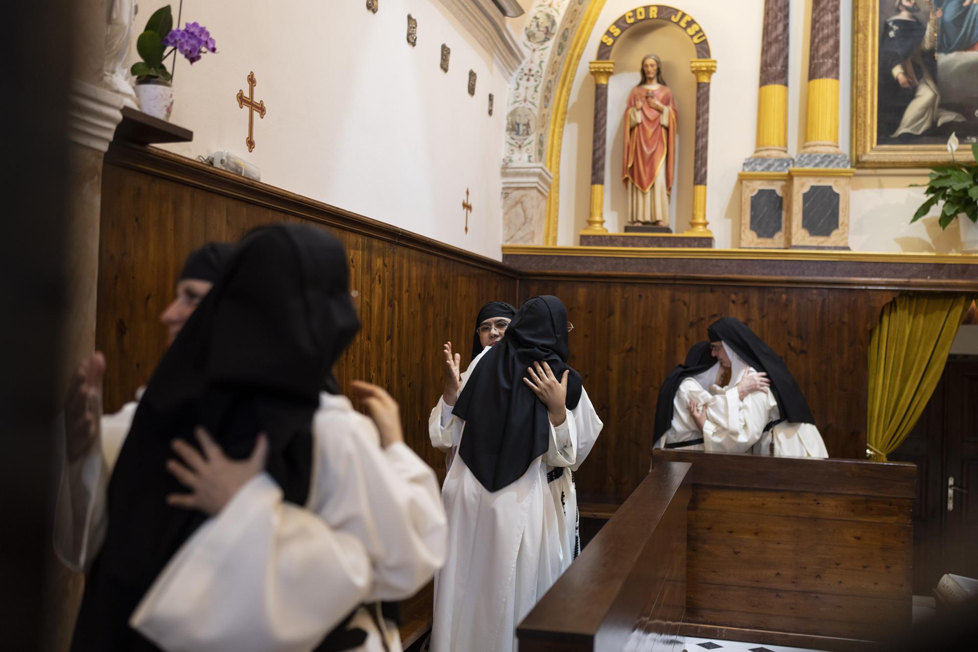 Las monjas se abrazan durante el signo de la paz en la Misa diaria en el Monasterio Católico de Santa Catalina en la isla griega de Santorini el jueves 14 de junio de 2022. (Foto AP/Petros Giannakouris)