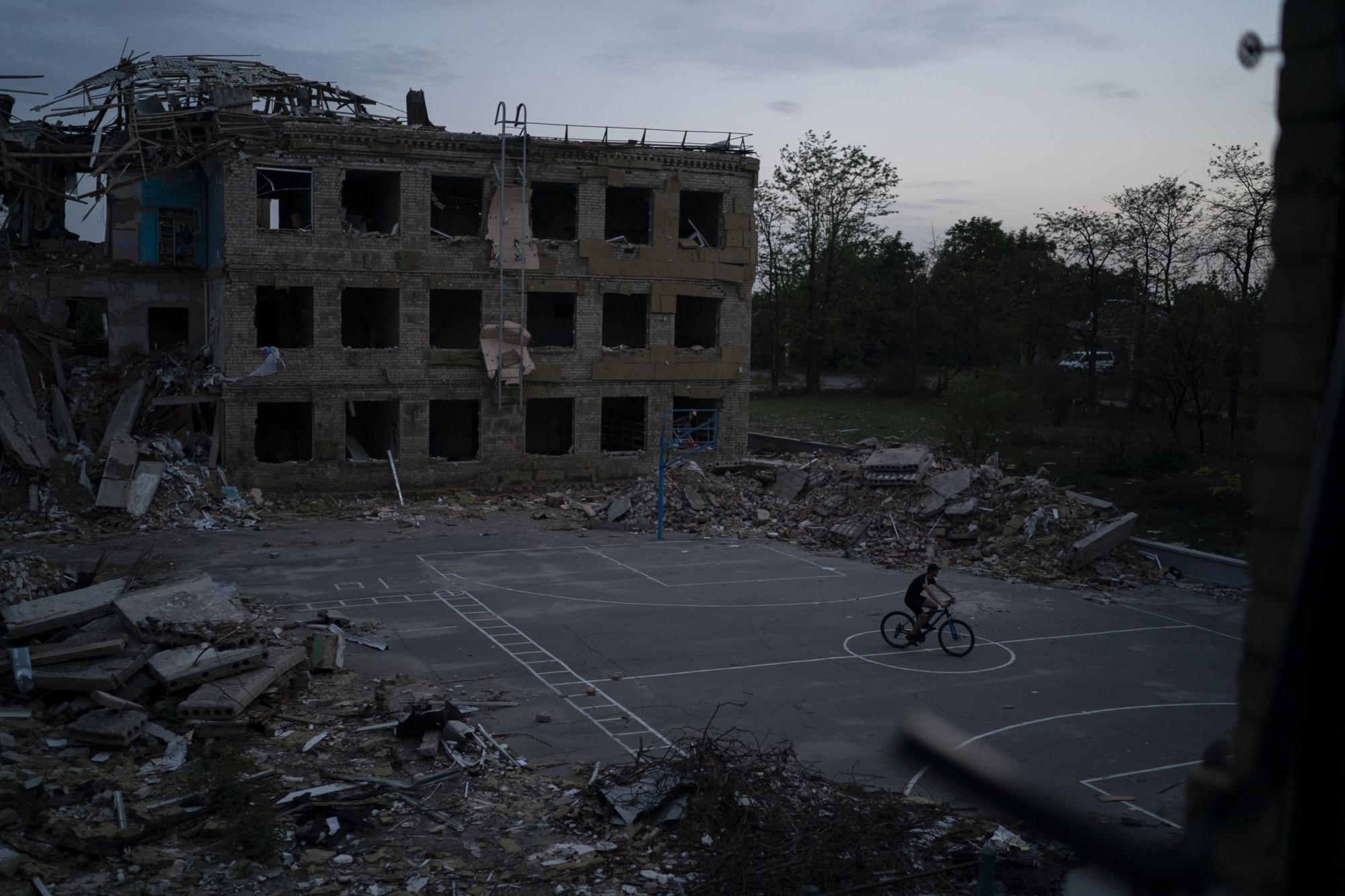 A man cycles through a courtyard of the destroyed School Number 23 after a Russian attack occurred in the second half of July, in Kramatorsk, Ukraine, Saturday, Aug. 27, 2022. (AP Photo/Leo Correa)