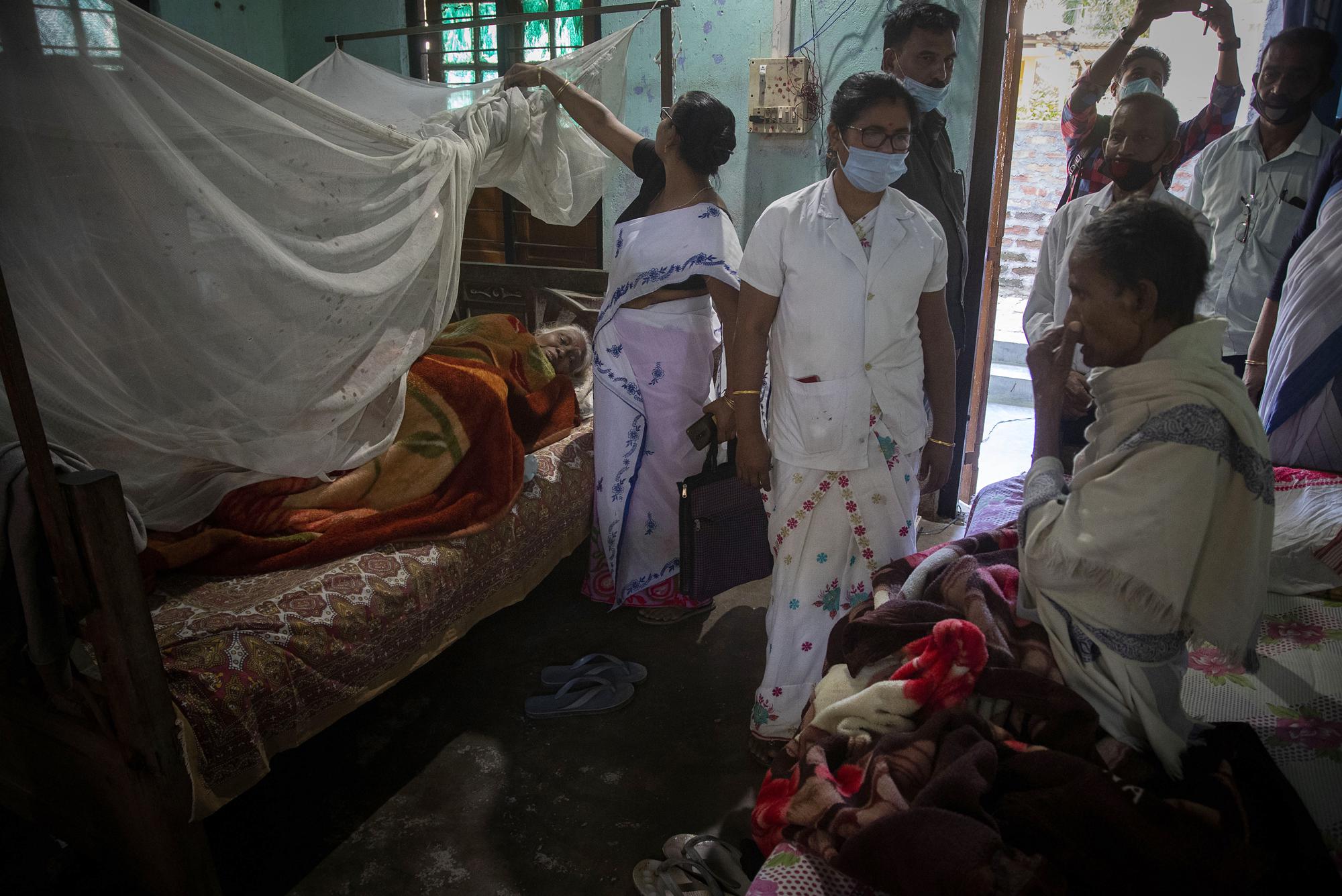 Health workers try to convince elderly people to receive the vaccine for COVID-19 during a door-to-door vaccination drive in Ouguri village, on the outskirts of Gauhati, India, Tuesday, Nov. 30, 2021. From South African undertakers to ultra-Orthodox Israeli rabbis, an unconventional cadre of people has joined global efforts to increase COVID-19 vaccination rates. Launching campaigns that traditionally have been the realm of public health authorities, they’re opening church doors, going door to door, village to village, touting the benefits of vaccination, sometimes making shots available on the spot.  (AP Photo/Anupam Nath)