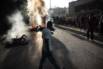 Transeúntes se reúnen alrededor de los cuerpos presuntos miembros de una pandilla a los que una turba prendió fuego tras ser detenidos por la policía mientras circulaban en un auto en la zona de Canape Vert, en Puerto Príncipe, Haití, el 24 de abril de 2023. (AP Foto/Odelyn Joseph)